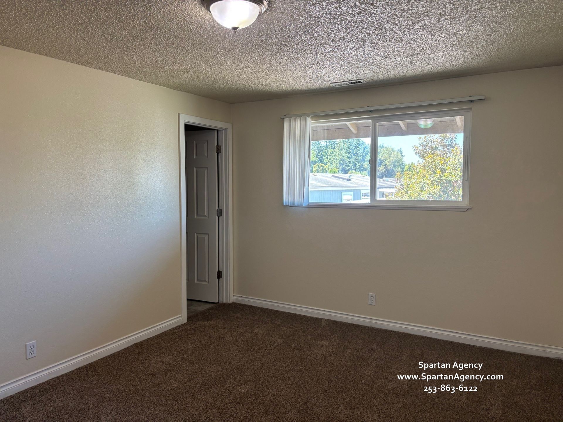 An empty bedroom with a window and a door