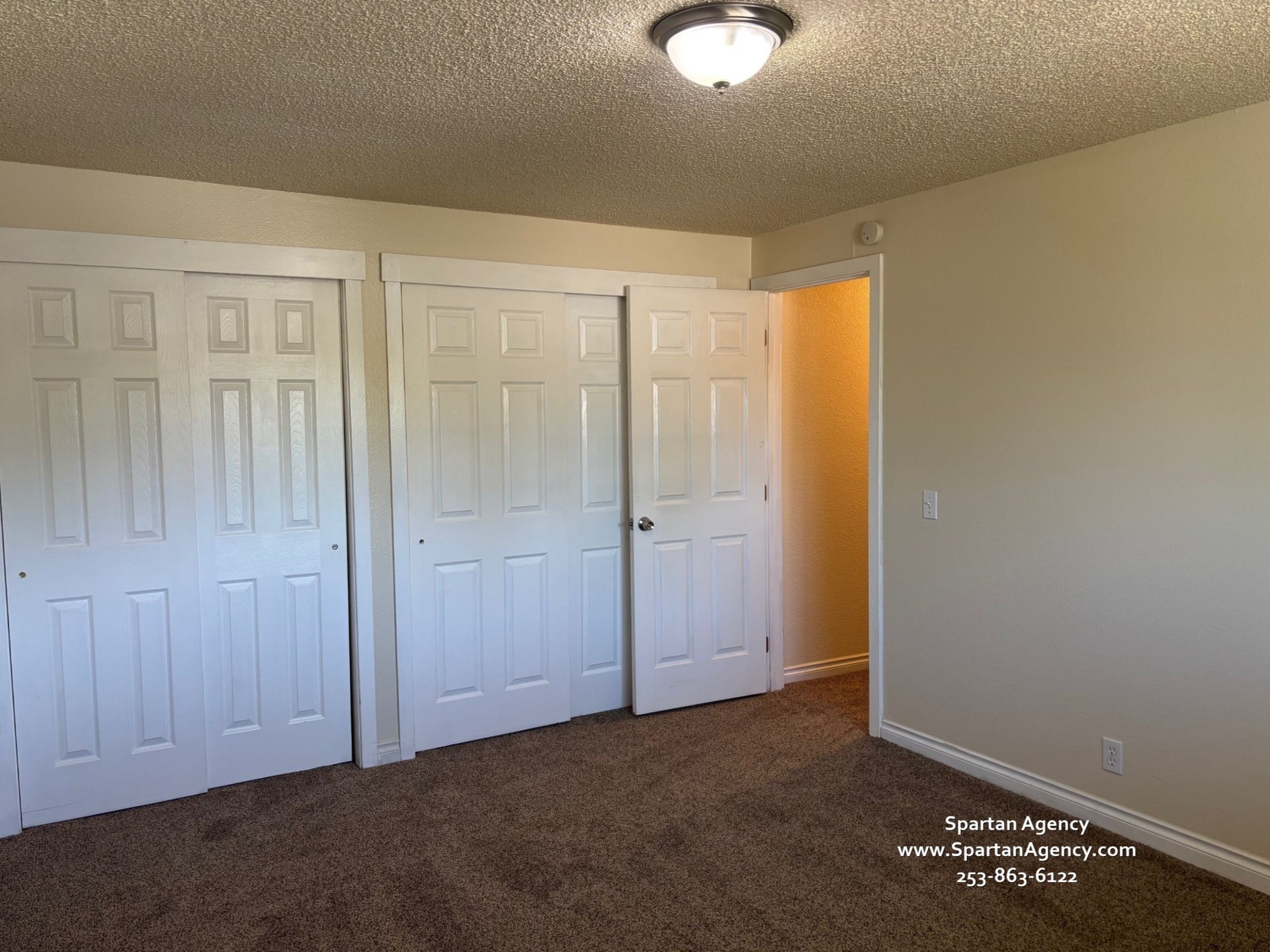 A bedroom with a lot of white doors and a light on the ceiling