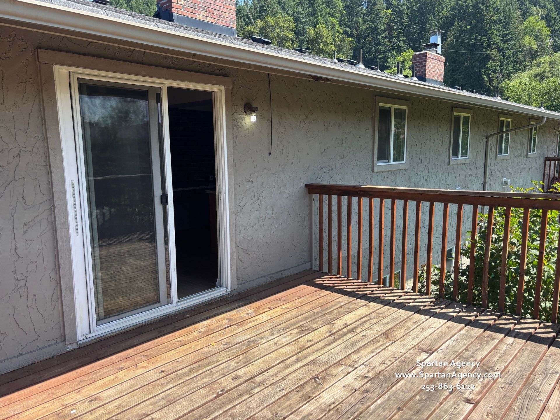 A wooden deck with a sliding glass door on the side of a house
