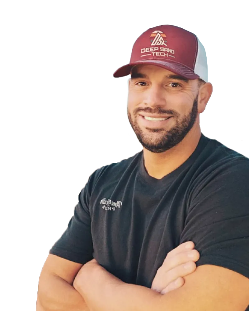 Man in maroon and white cap, arms crossed, smiling, wearing a black t-shirt.