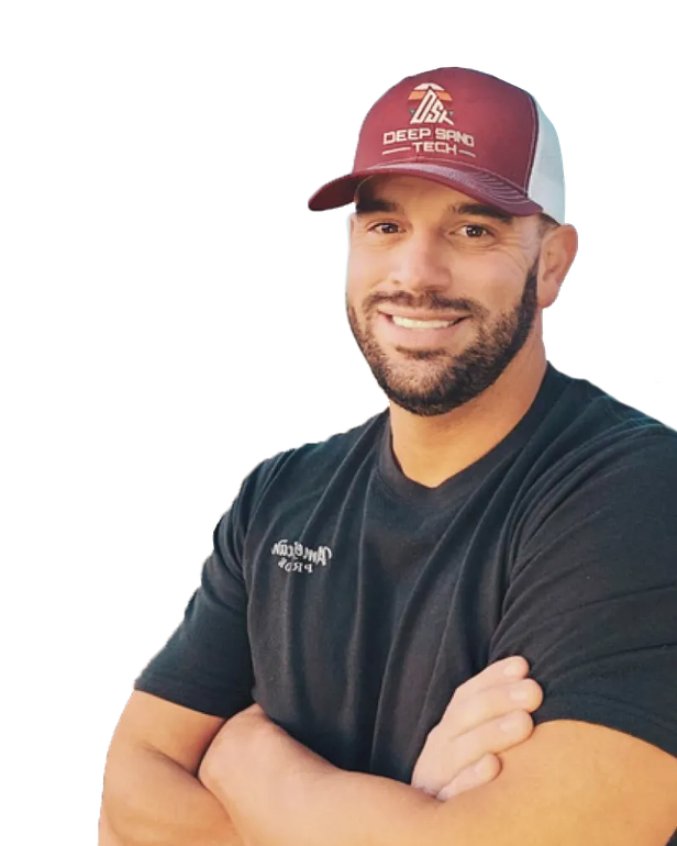 Man in maroon and white cap, arms crossed, smiling, wearing a black t-shirt.