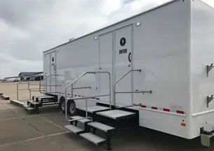 A white trailer with stairs attached to it is parked in a parking lot