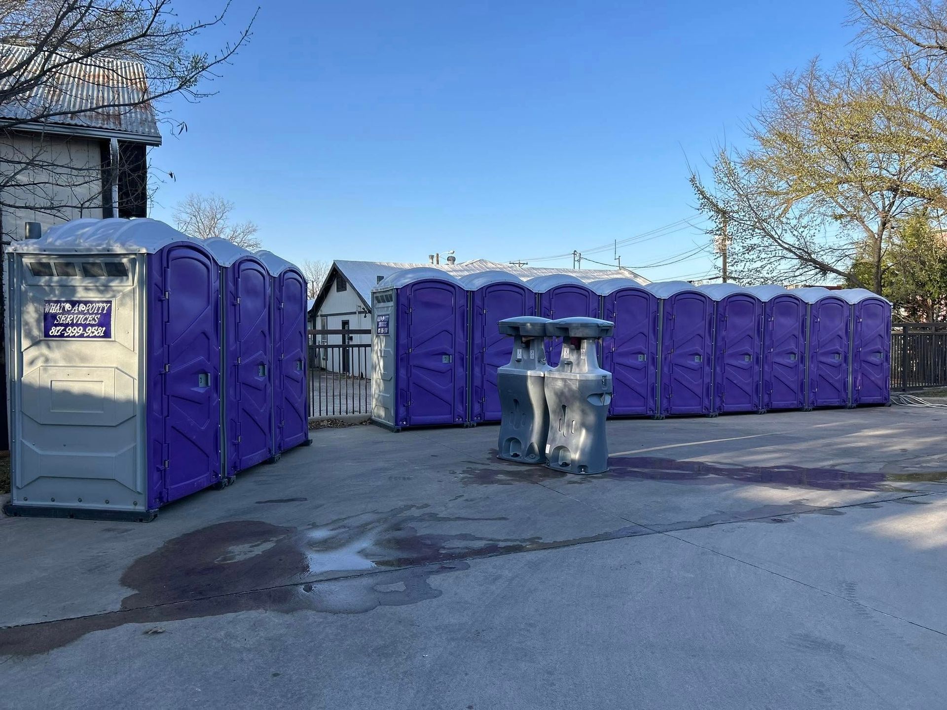 Row of purple portable toilets on a snowy outdoor surface.