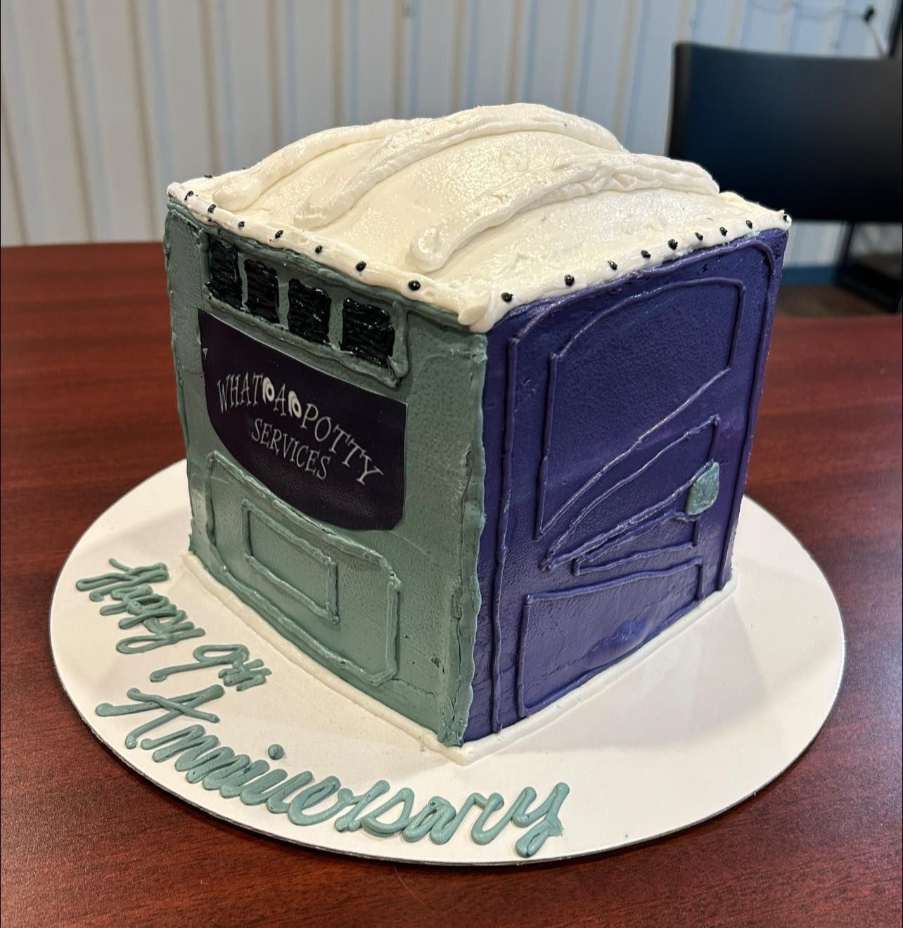 Cake decorated as a porta-potty, celebrating a company's 9th anniversary. Features blue, green, and white frosting.