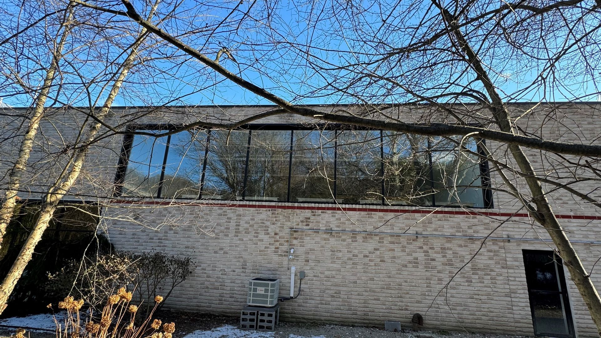 A large brick building with a lot of windows and trees in front of it.