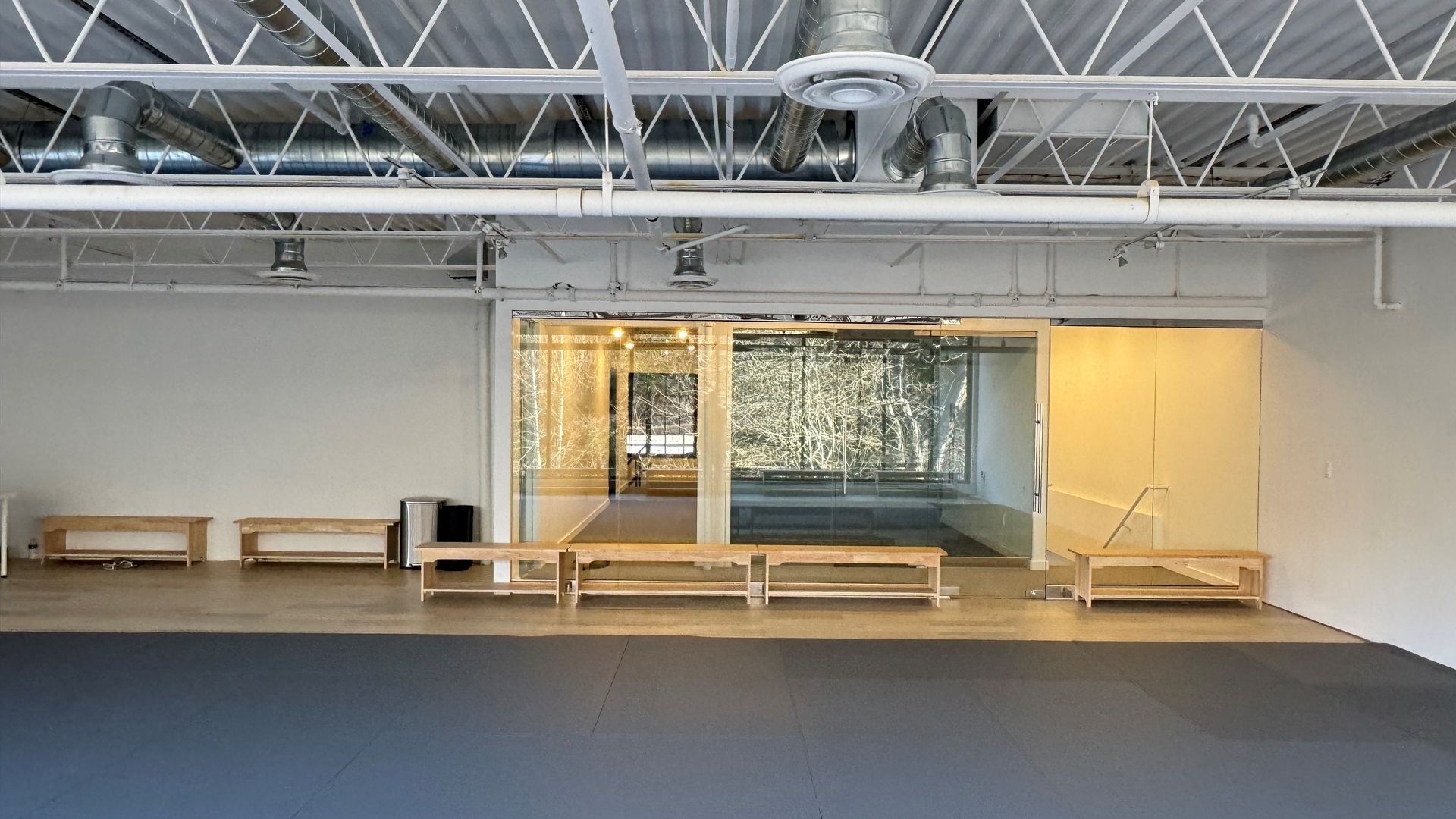 A large empty room with benches and a sliding glass door.