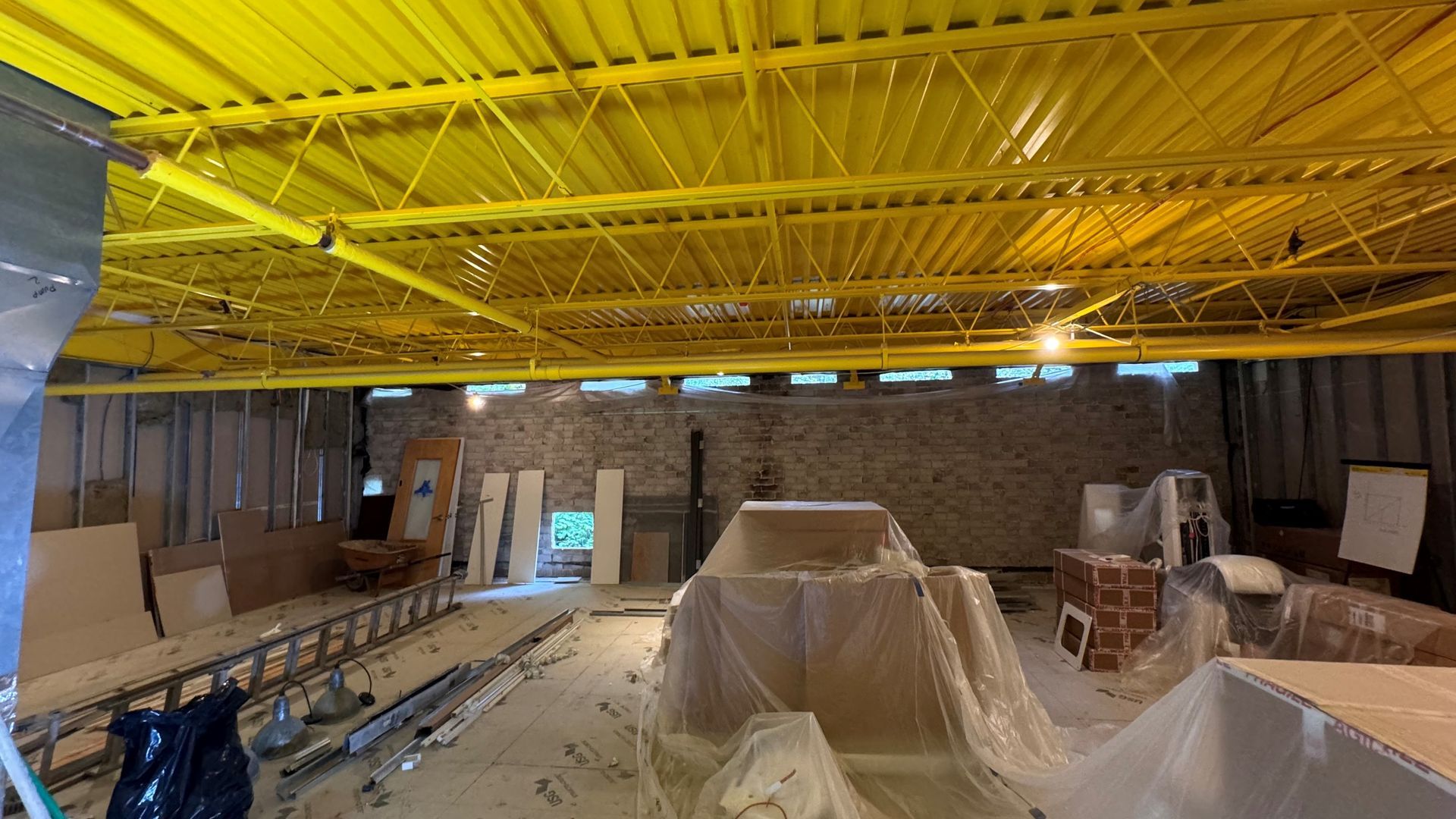 A building under construction with a yellow ceiling and a brick wall.
