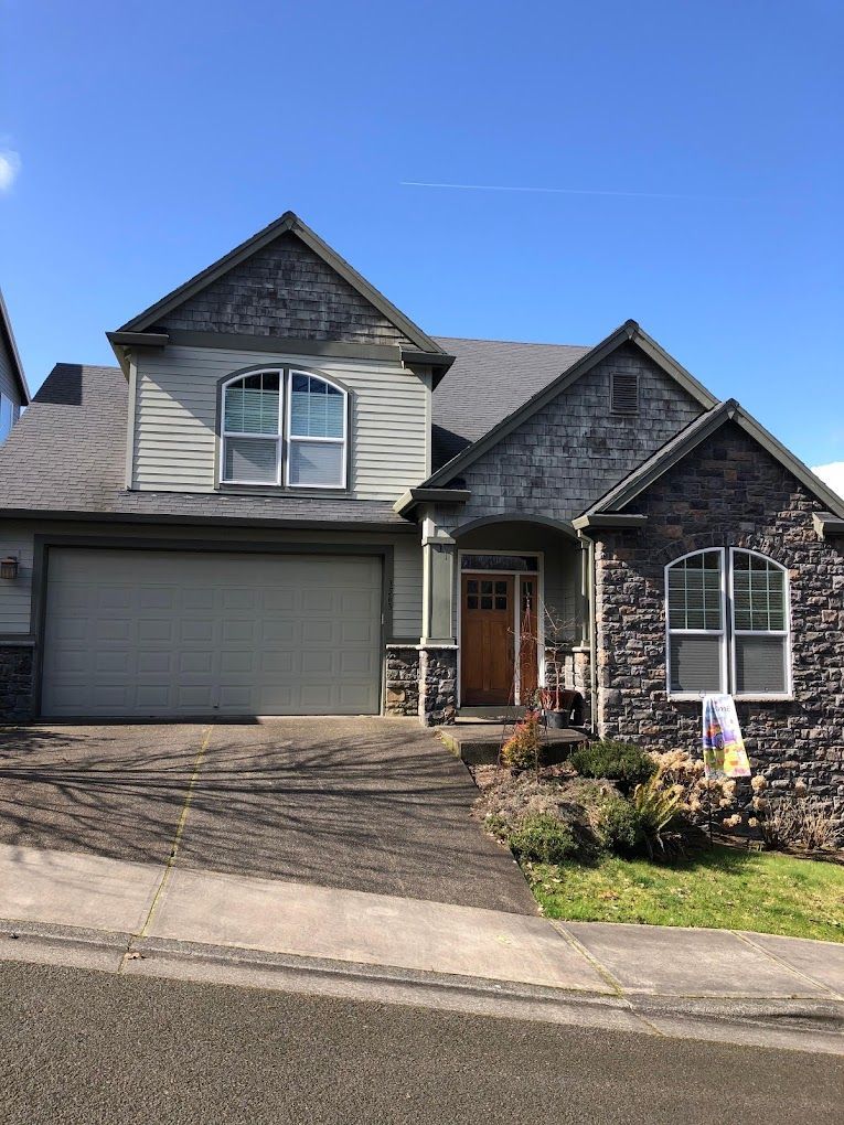 A large house with a garage and a sign in front of it.
