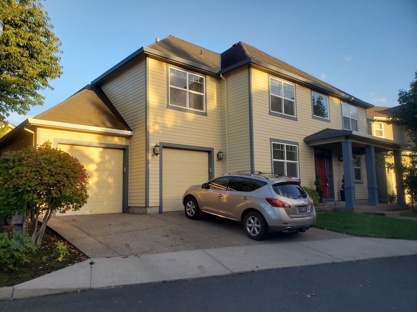 A car is parked in front of a large house.