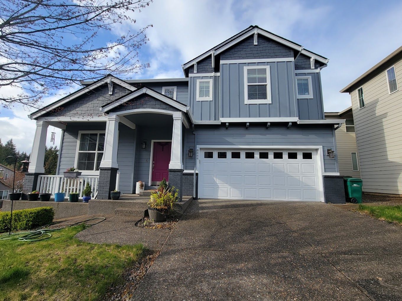 A gray house with a white garage door and a pink door.