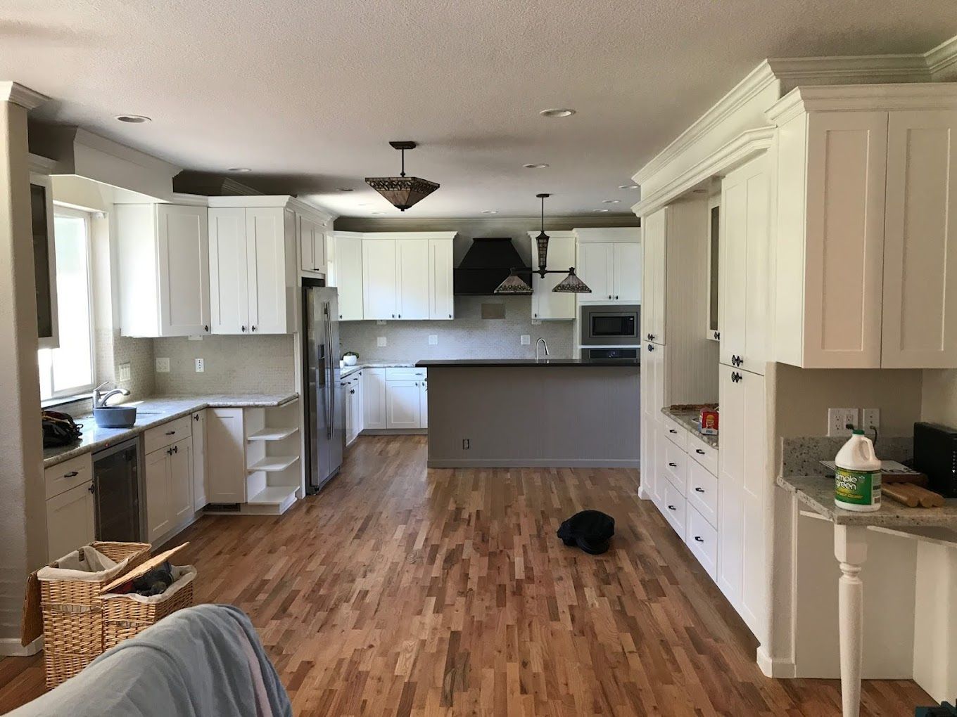 A kitchen with white cabinets and hardwood floors.