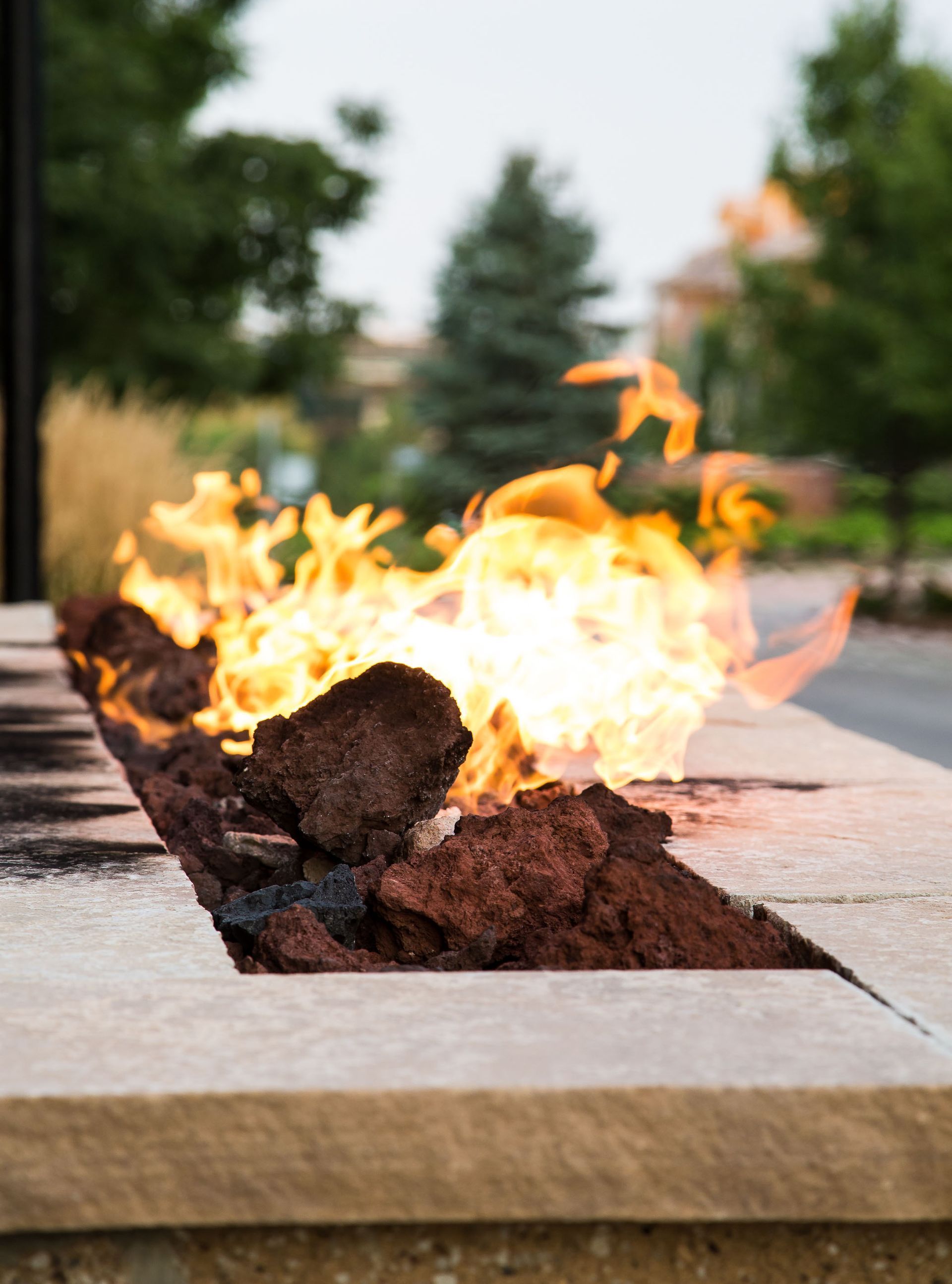 Modern fire pit with bright flames on a stone patio, outdoor backyard setting