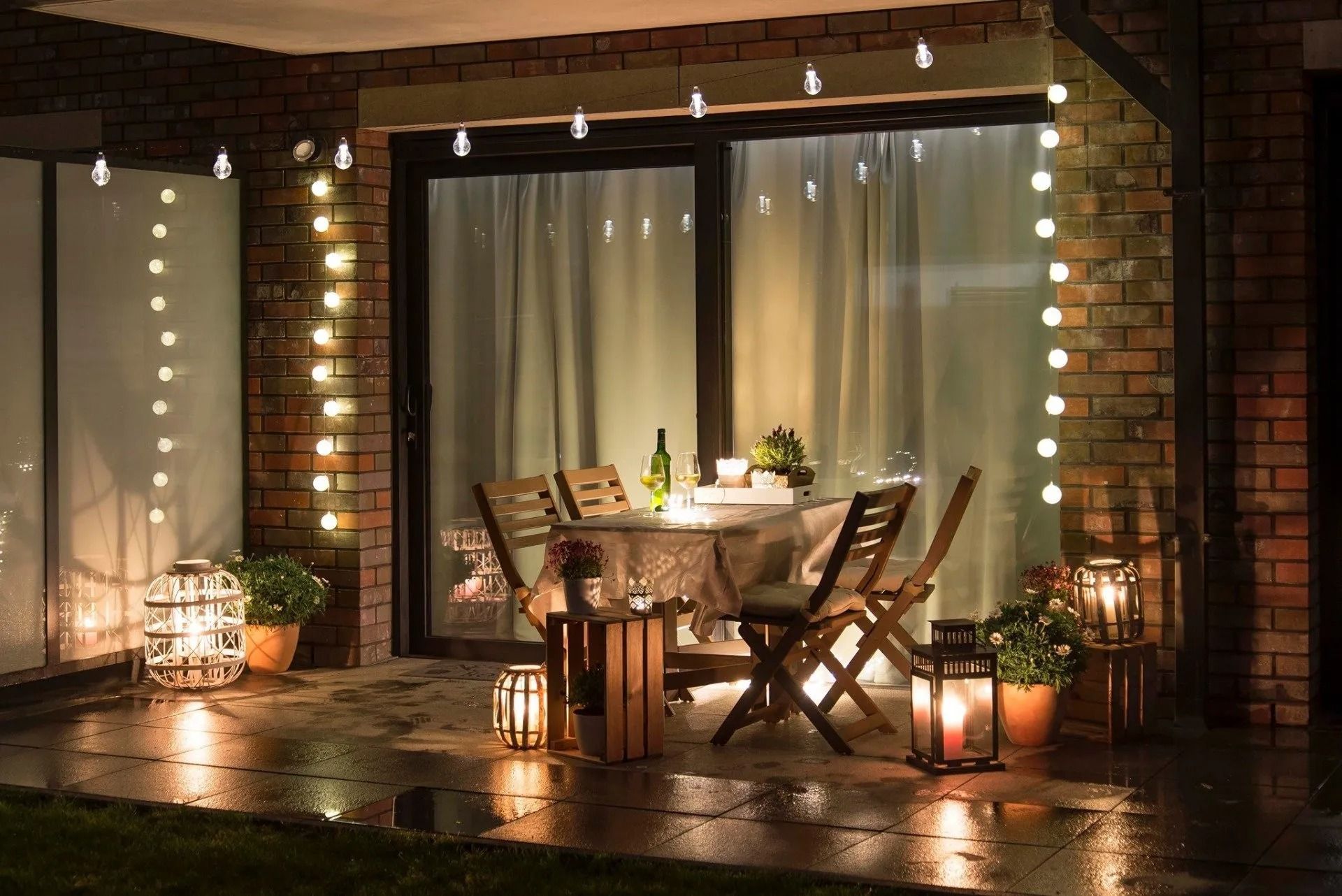 Cozy outdoor patio dining area with string lights, wooden chairs, and a small table at dusk