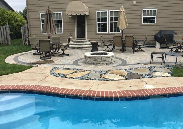 Backyard patio with a swimming pool, fire pit, outdoor seating, and a covered door at the house.
