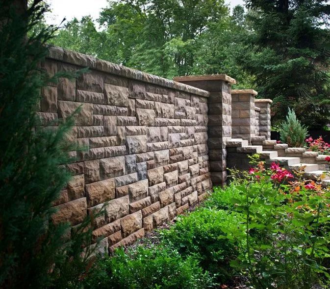 Stone retaining wall beside lush green garden with steps and flowering plants