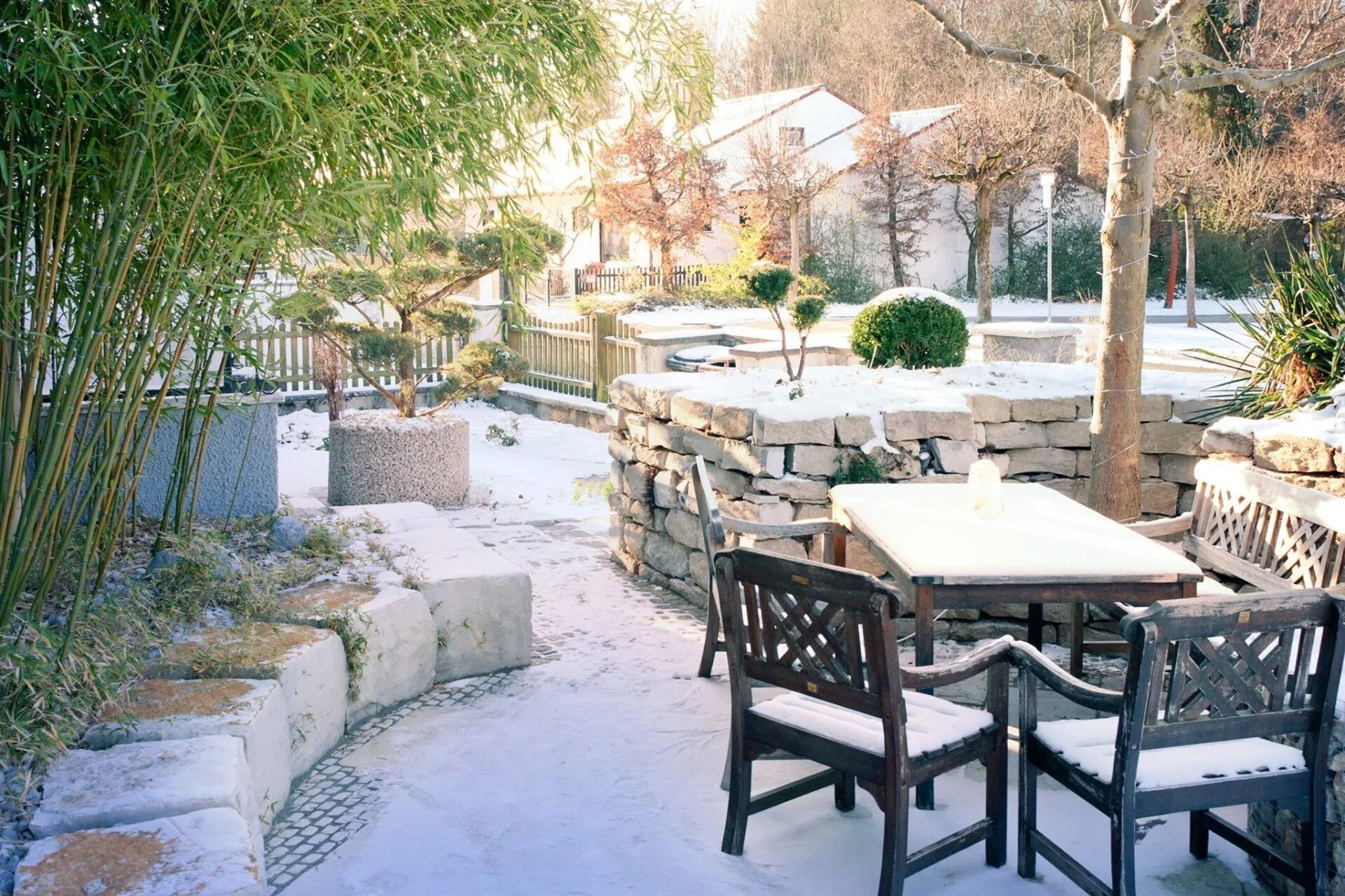 Outdoor café patio with wooden tables and chairs beside a snowy garden path