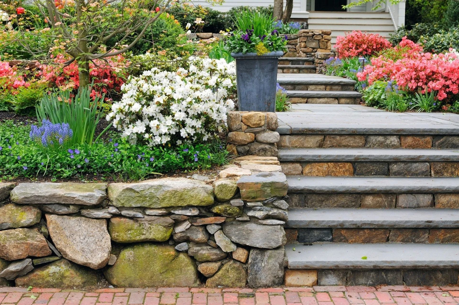 Stone garden steps bordered by colorful flowers and stacked rock retaining walls