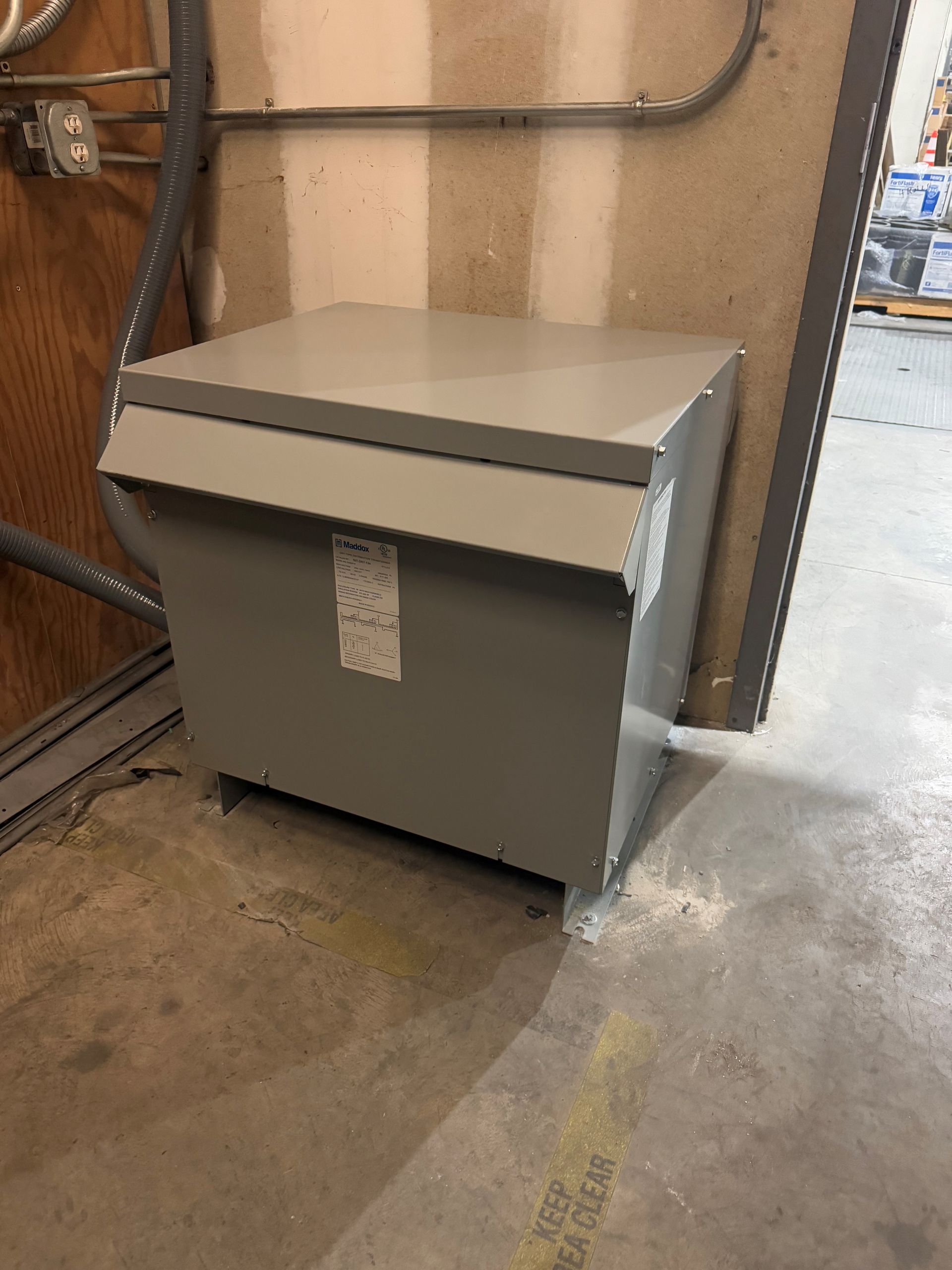 A transformer is sitting on the floor in a room next to a wall.