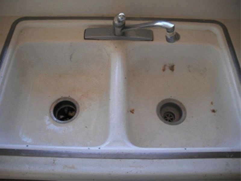 White double basin kitchen sink with faucet, grimy and stained.