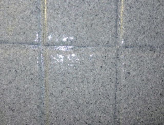 Gray tiled floor with white patches on the tiles and grout lines.