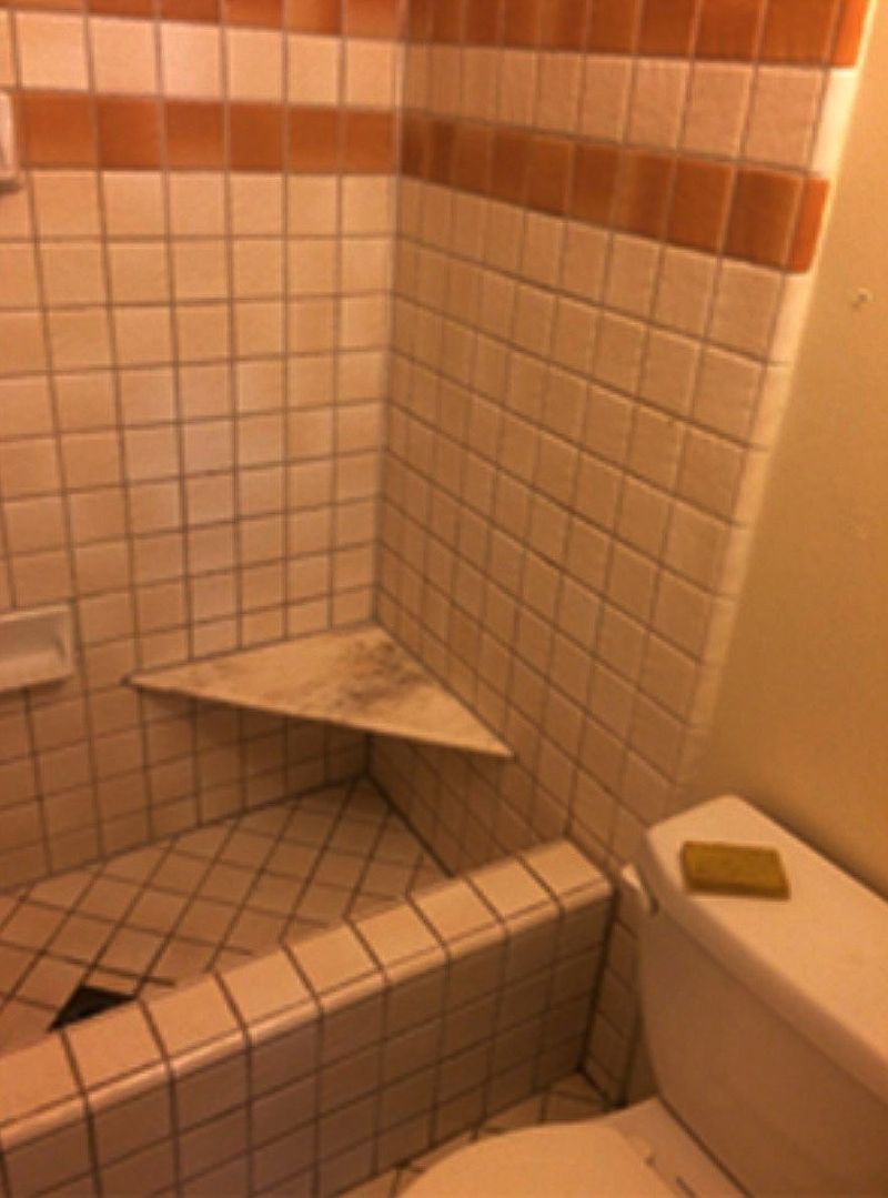 Bathroom with tiled walls, corner shelf, and toilet. Beige and orange tiles.
