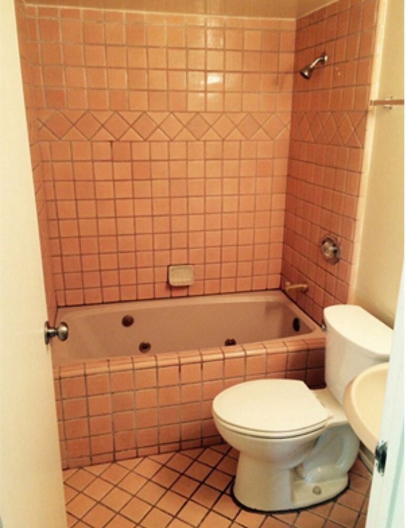 Bathroom with pink tile walls and a jacuzzi tub, next to a toilet.