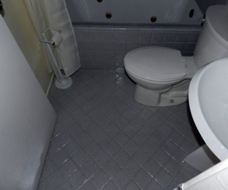 Bathroom with gray tiled floor, toilet, sink, and bathtub.