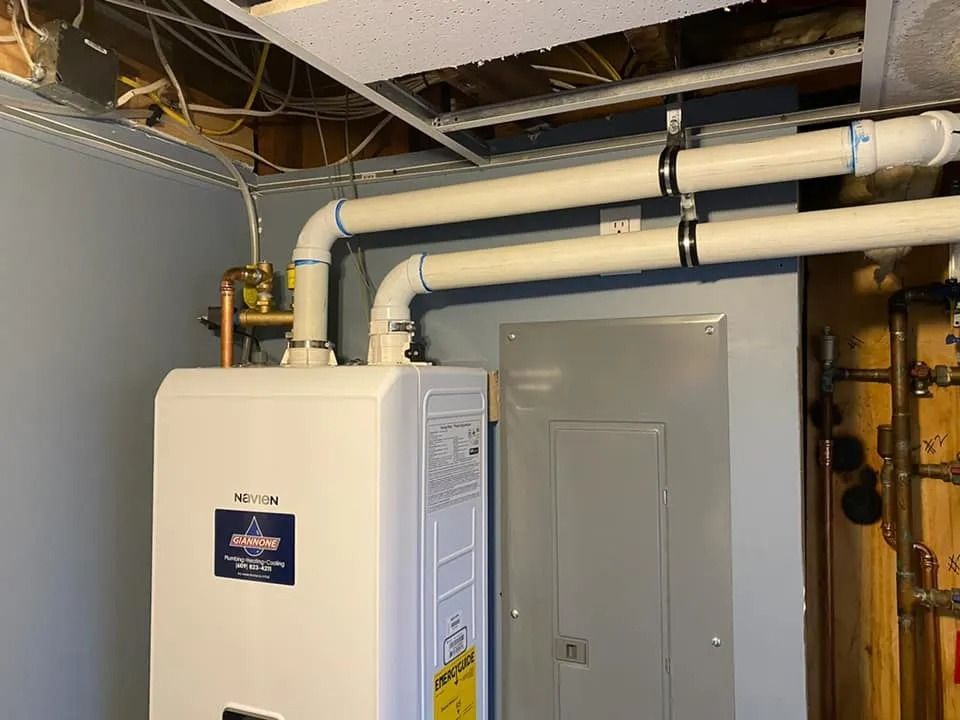Basement utility room with a white boiler, exposed pipes, and electrical panel.