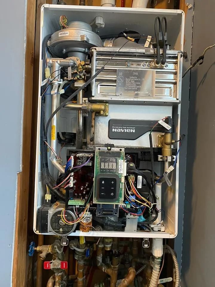 Open electrical control panel with wires, circuit boards, and metal components inside a cabinet
