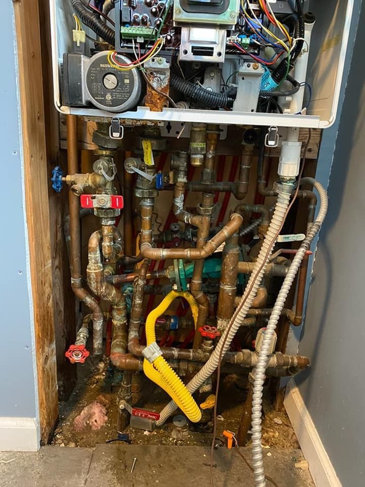 Open utility closet with exposed plumbing pipes, valves, and water meter components.