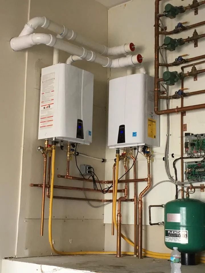 Wall-mounted boilers and copper pipes in a utility room, with a green expansion tank on the right.