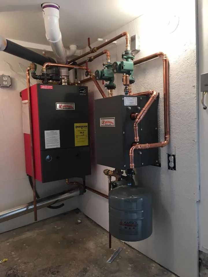 Wall-mounted boiler and copper plumbing in a utility room with a gray tank below