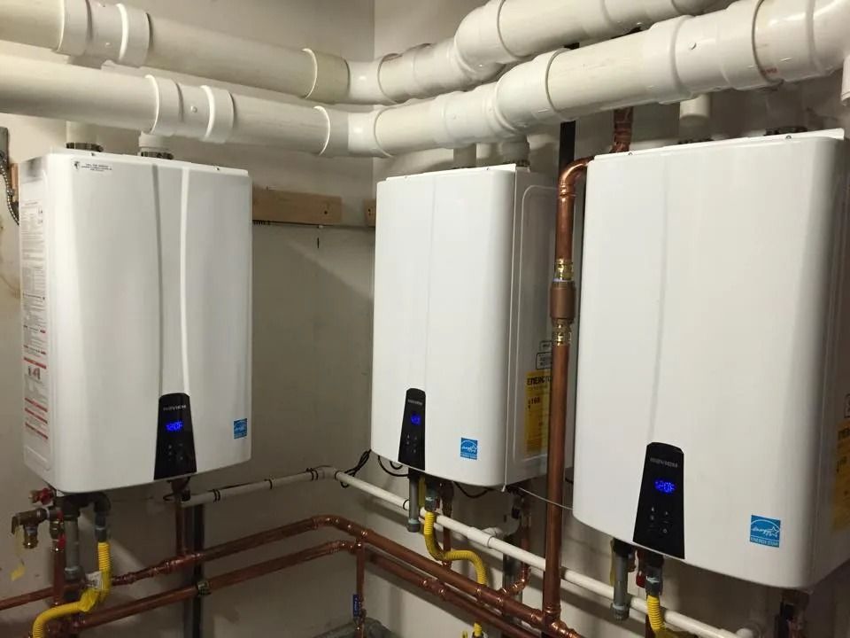 Three white wall-mounted water heaters with copper pipes in a utility room