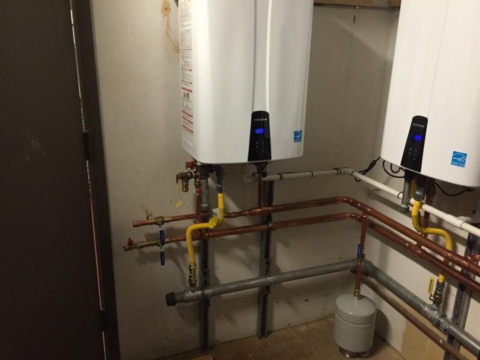 Utility room with two wall-mounted water heaters, copper pipes, and a gas line.