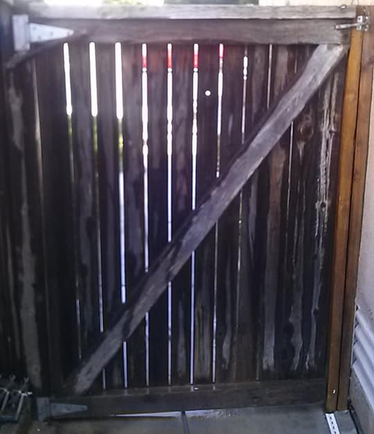 Wooden gate with diagonal brace, vertical planks, and a latch.