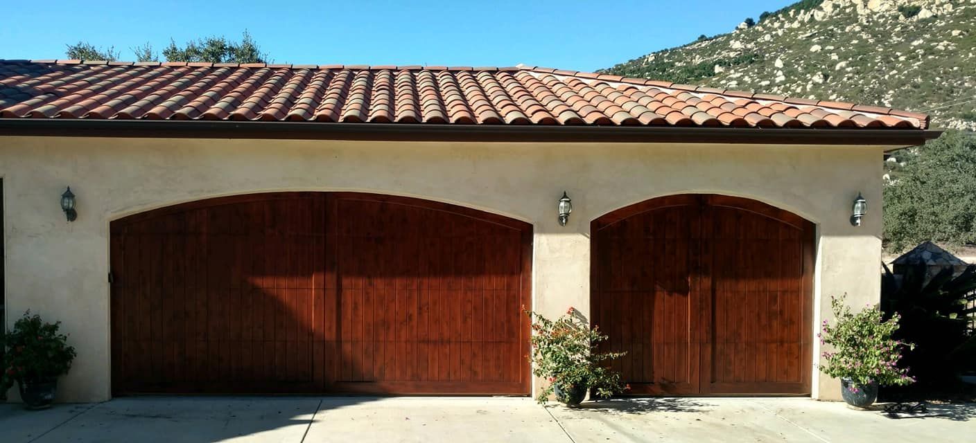 Tan garage with terracotta tile roof and brown wooden doors.