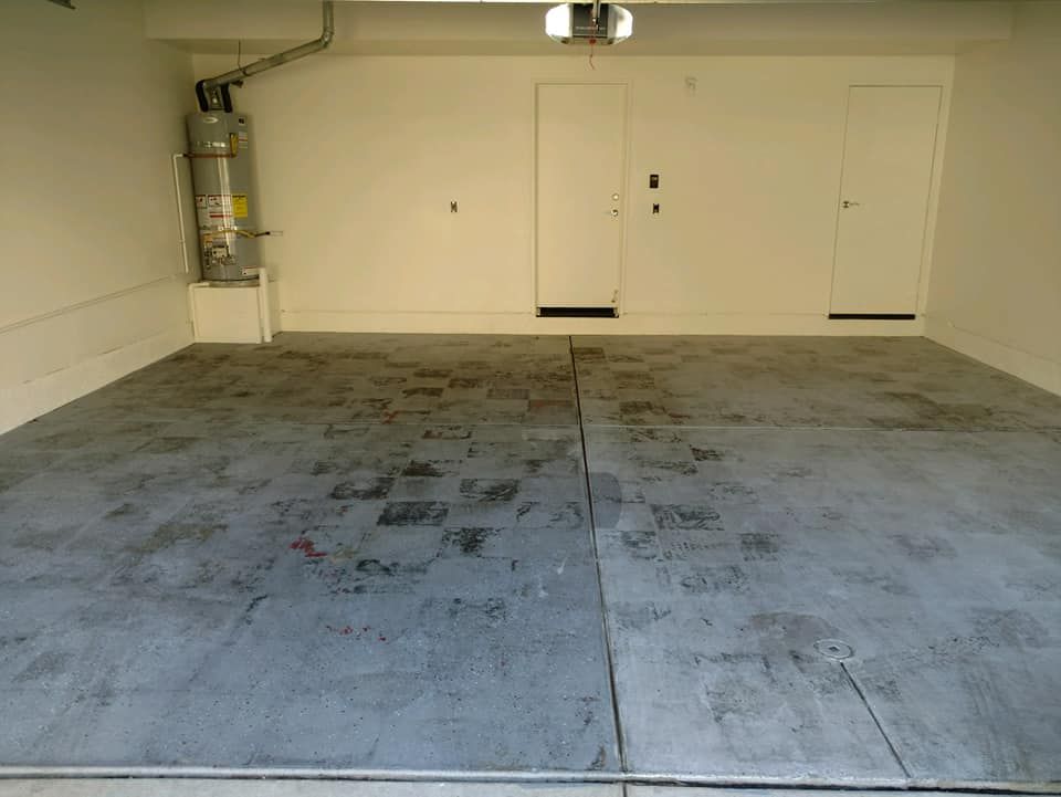 Empty garage with concrete floor, water heater, and doors.