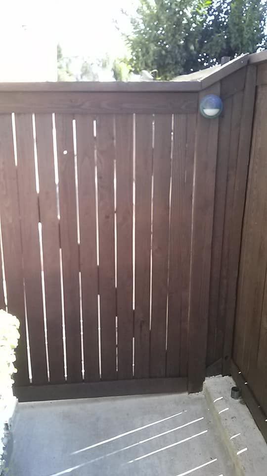 Wooden fence in brown with a security light, next to a concrete patio.