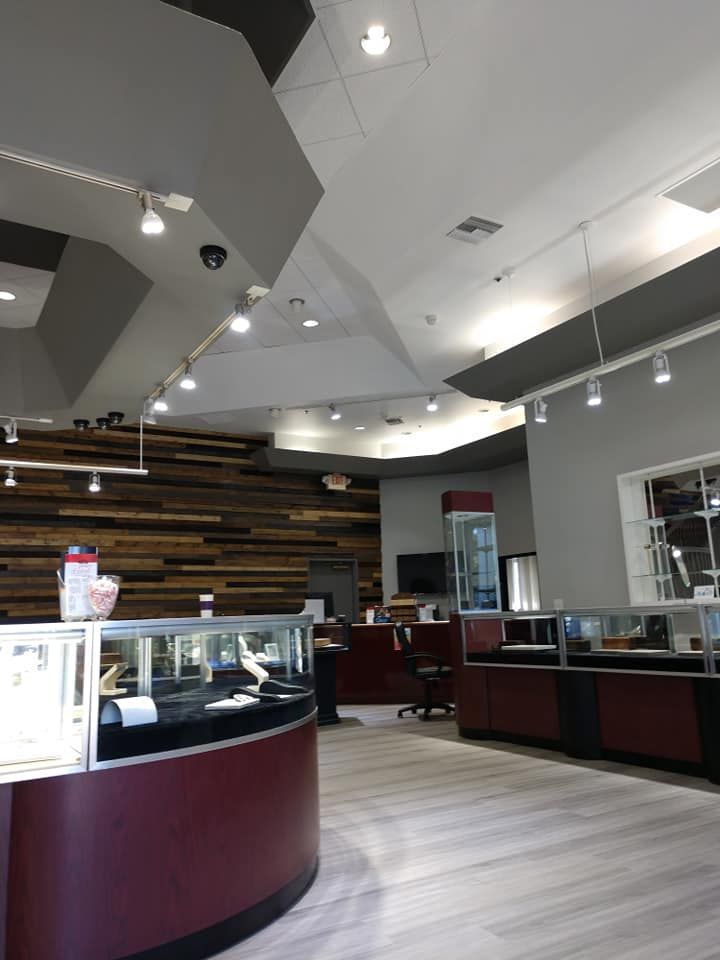 Interior of jewelry store with wood-paneled wall, glass display cses, and burgundy accents.