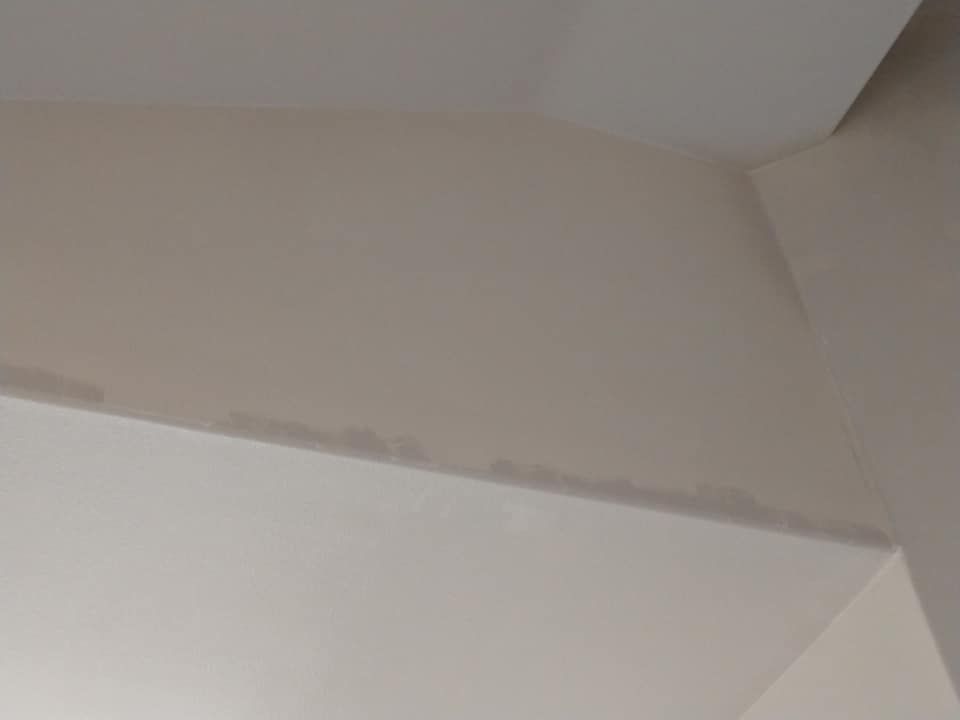 Off-white walls and ceiling meet at an angle, with a darker band along one edge.