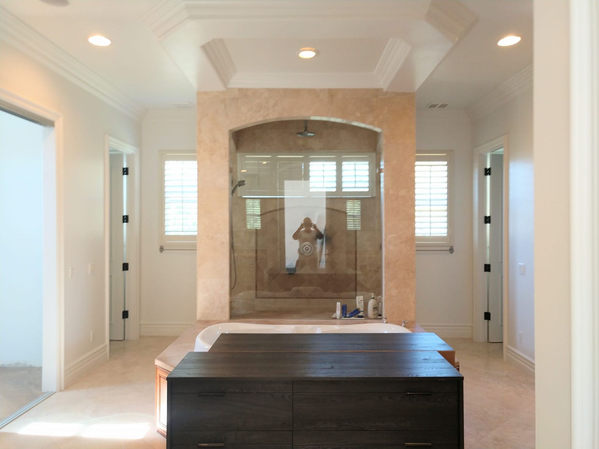 Spacious bathroom with a central shower, light walls, and dark wood dresser.