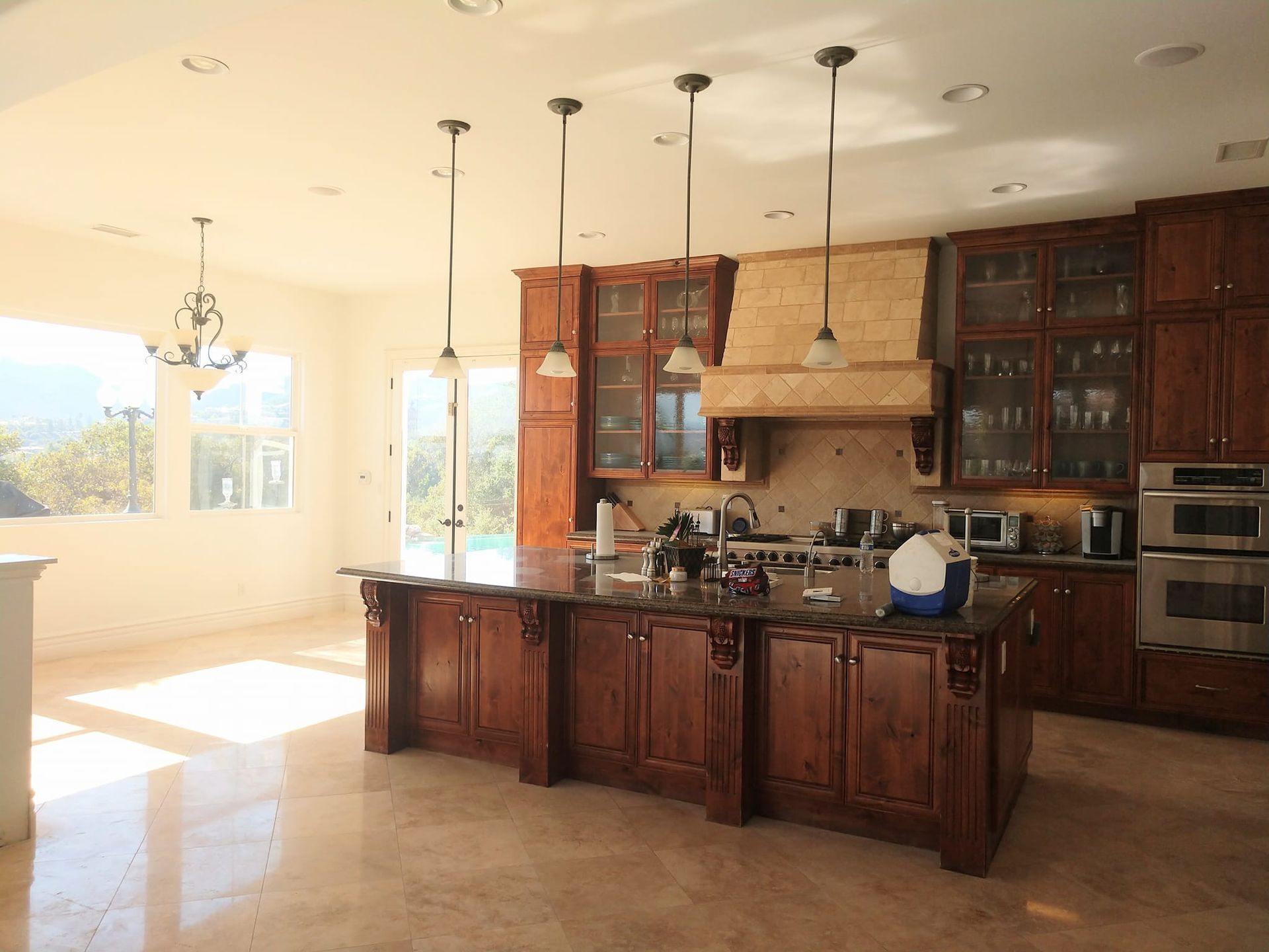 Spacious kitchen with a large island, wood cabinets, and pendant lights; natural light streams in.