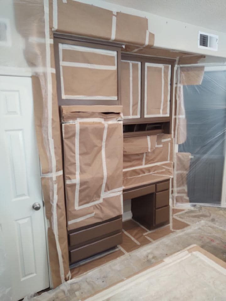 Cabinets and desk covered in brown paper and tape, prepped for painting.