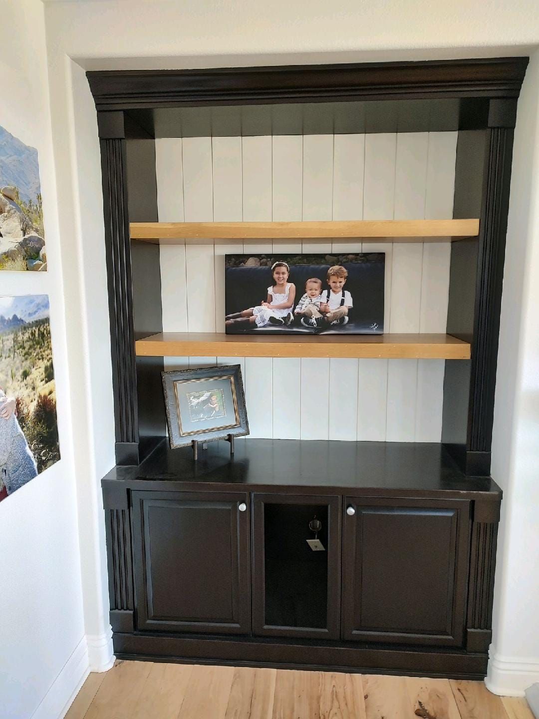 Dark brown built-in bookcase with light wood shelves and a family photo.
