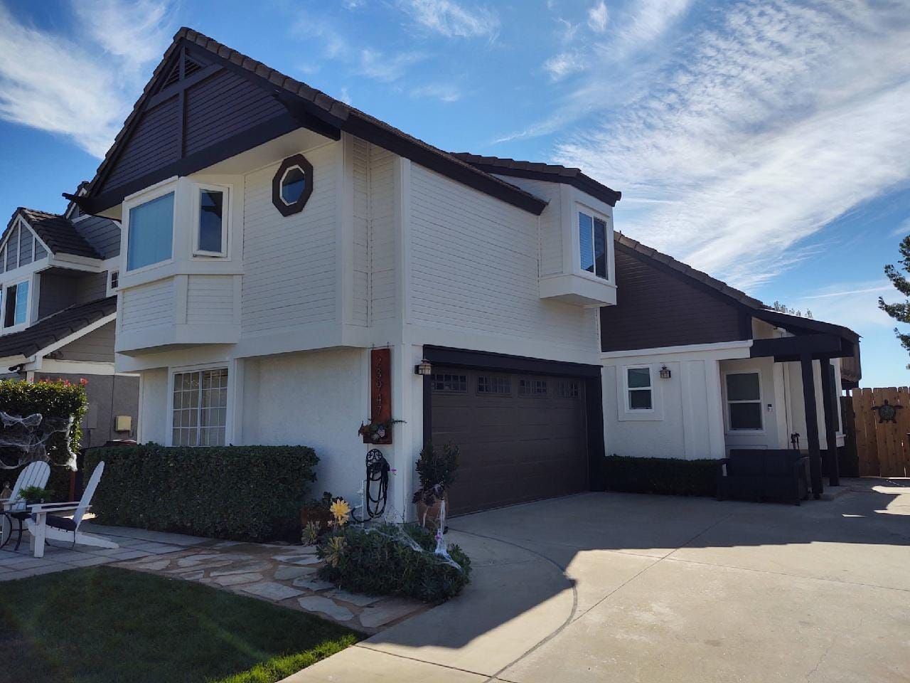 Two-story house with white and brown exterior on a sunny day.