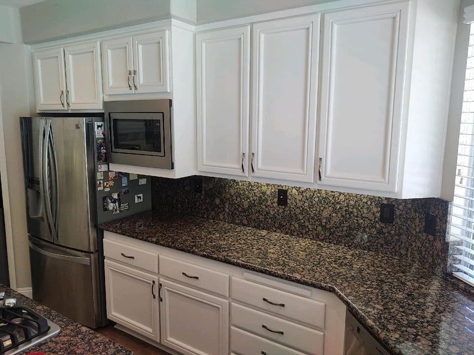 White kitchen cabinets and appliances against a patterned countertop and backsplash.