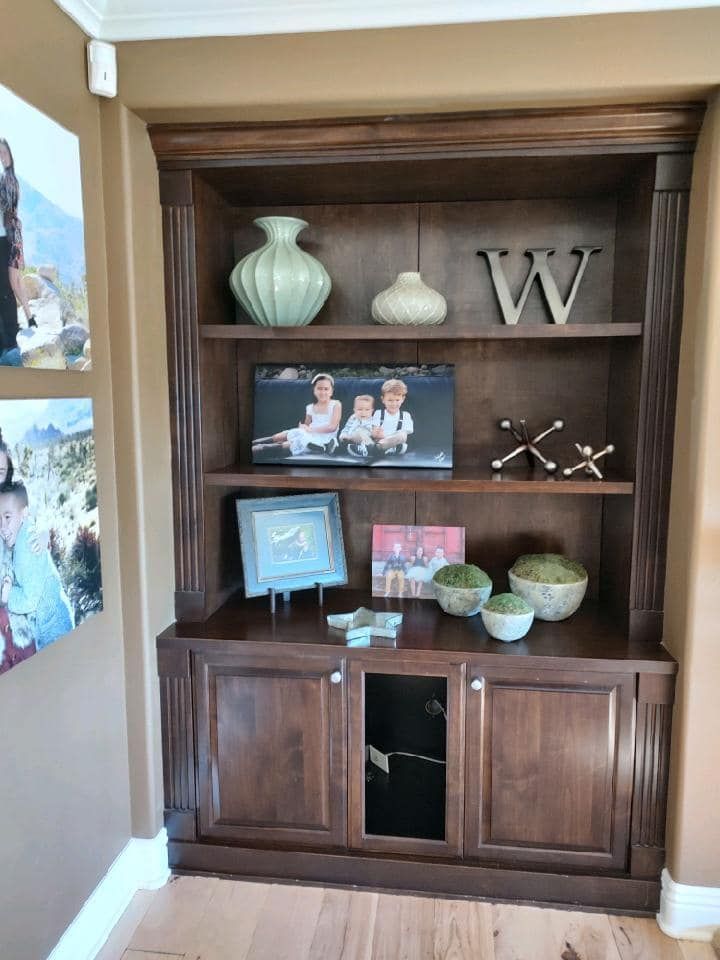 A dark brown wooden bookshelf with decorative items and framed photos.