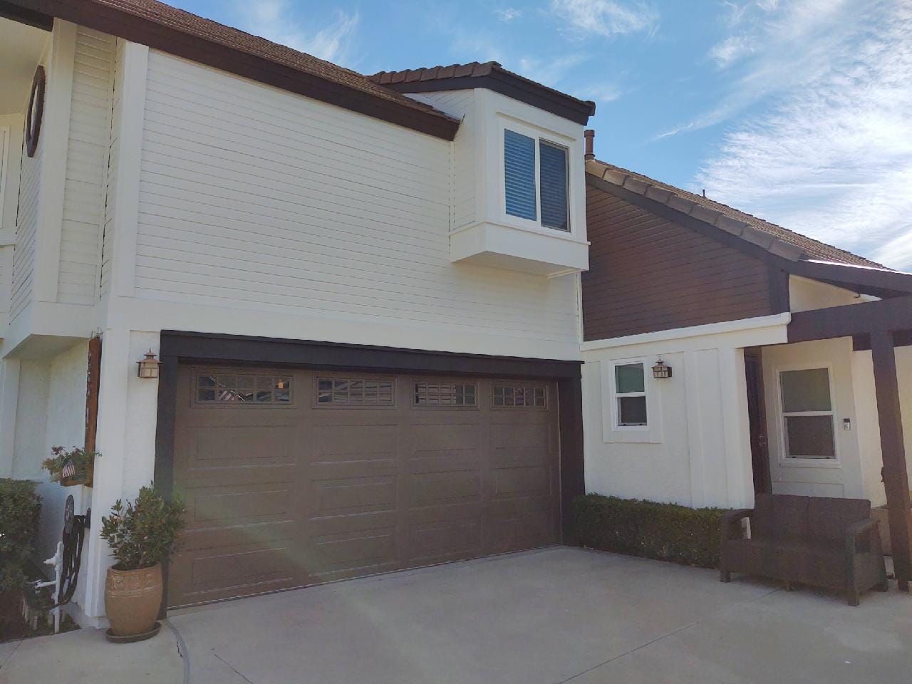 Two-story house with a brown garage door, white walls, brown trim, and a blue sky.