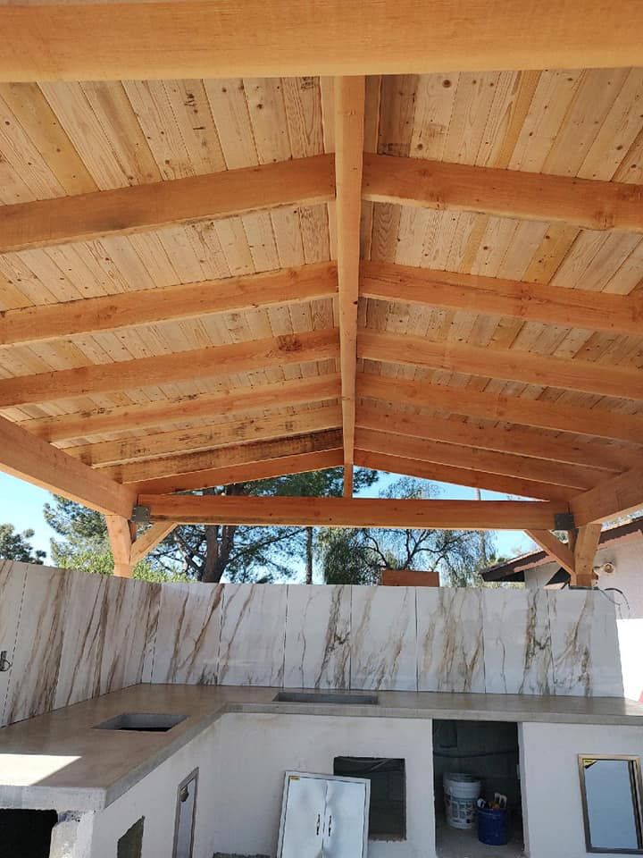 Wooden patio roof over an outdoor kitchen with a marble backsplash.