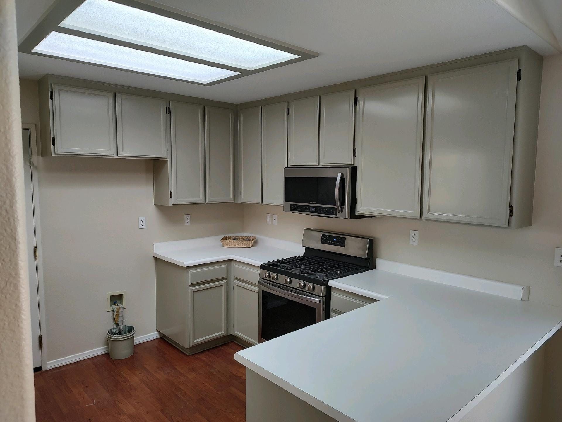 Kitchen with gray cabinets, white countertops, and stainless steel appliances.